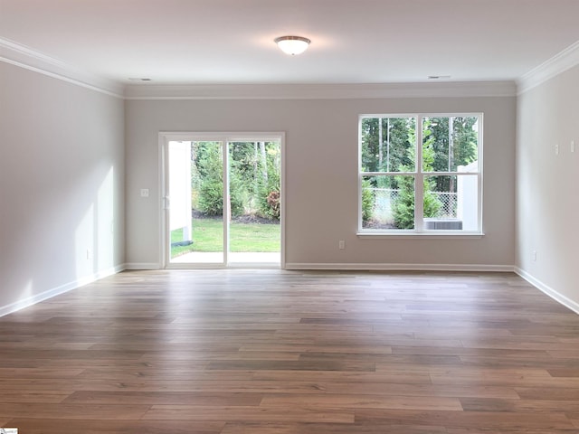 spare room with crown molding, wood finished floors, and baseboards