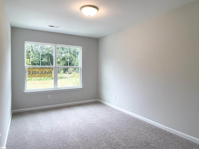 carpeted spare room featuring visible vents and baseboards