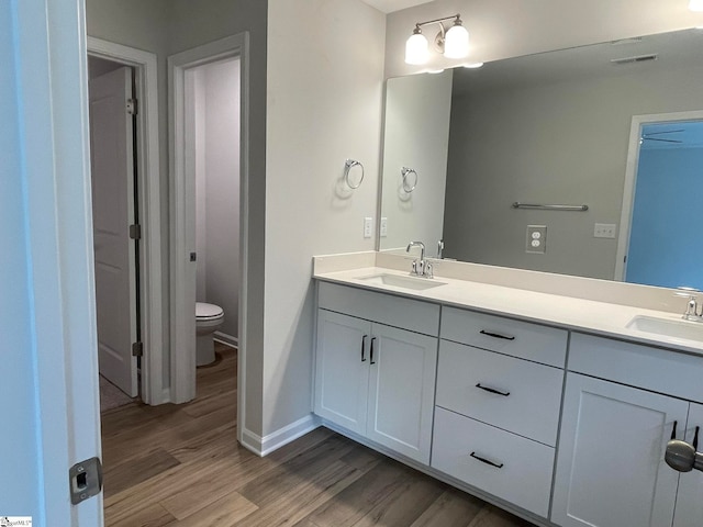 bathroom featuring visible vents, toilet, wood finished floors, and a sink