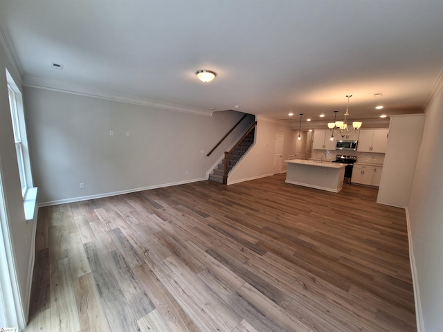 unfurnished living room with ornamental molding, hardwood / wood-style floors, and an inviting chandelier