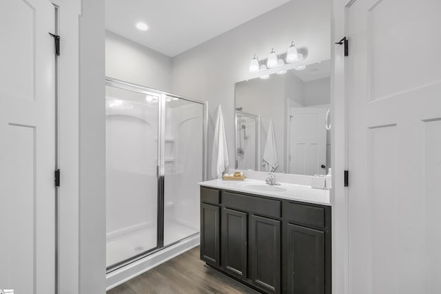 bathroom with a stall shower, vanity, and wood finished floors