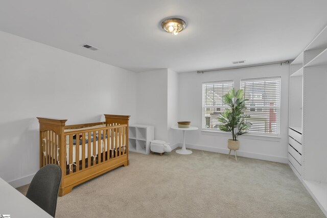 carpeted bedroom featuring a nursery area