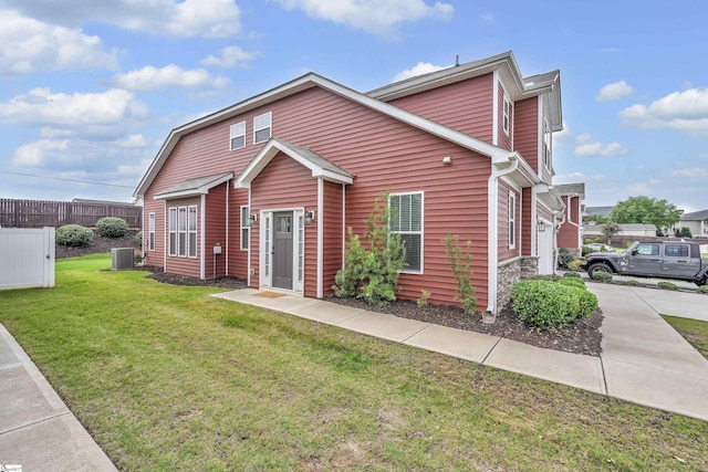 view of front of property featuring fence, a front lawn, and central air condition unit