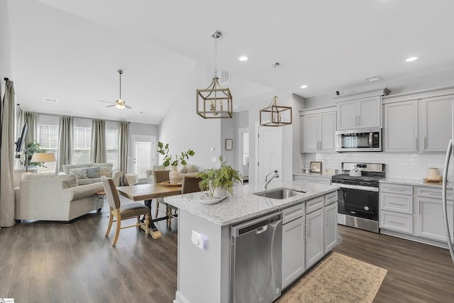 kitchen featuring stainless steel appliances, dark wood-style flooring, a sink, open floor plan, and decorative backsplash