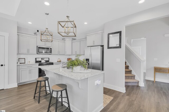 kitchen featuring tasteful backsplash, stainless steel appliances, hardwood / wood-style floors, and an island with sink