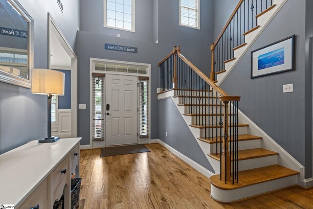 entryway with light hardwood / wood-style flooring, plenty of natural light, and a towering ceiling