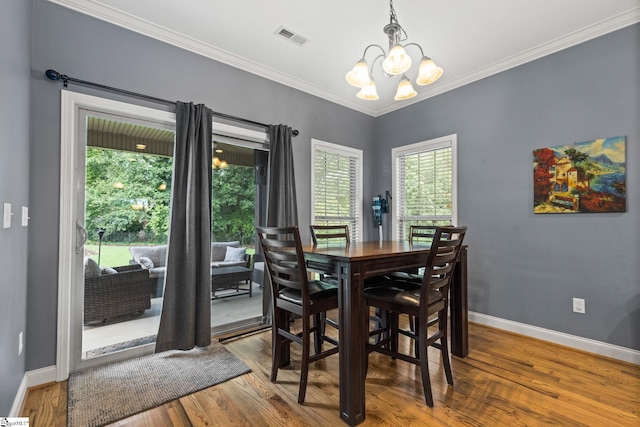 dining area featuring wood-type flooring, crown molding, and an inviting chandelier