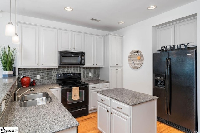 kitchen with black appliances, white cabinets, decorative backsplash, sink, and light hardwood / wood-style floors