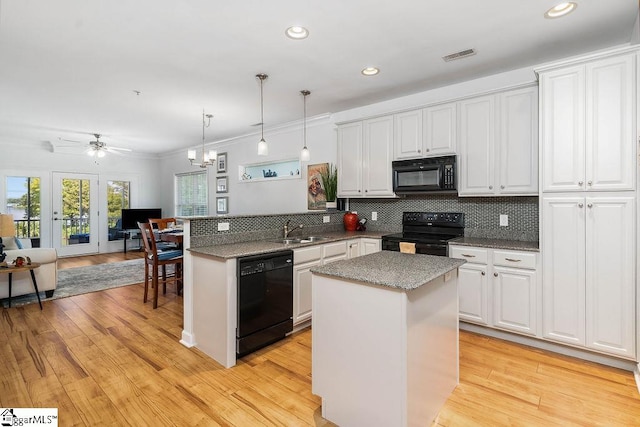 kitchen with white cabinetry, light wood-type flooring, ceiling fan with notable chandelier, black appliances, and hanging light fixtures