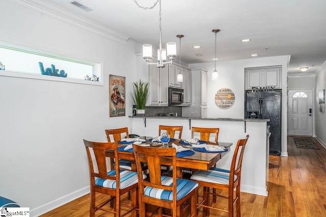 dining space with a notable chandelier, crown molding, and hardwood / wood-style floors