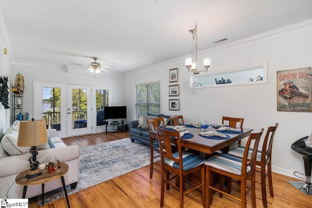 dining area featuring ceiling fan with notable chandelier, light hardwood / wood-style floors, french doors, and ornamental molding