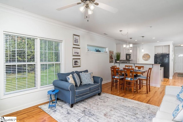 living room with light hardwood / wood-style floors, ornamental molding, and ceiling fan with notable chandelier