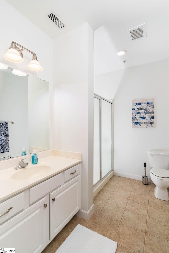 bathroom with tile patterned floors, vanity, a shower with shower door, and toilet