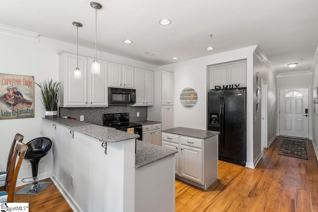 kitchen with crown molding, tasteful backsplash, light wood-type flooring, black appliances, and decorative light fixtures