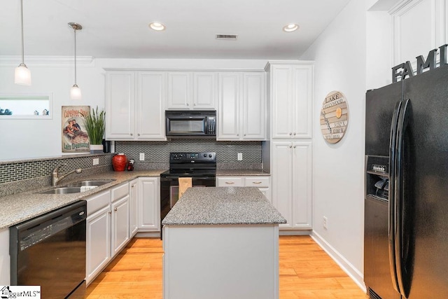 kitchen featuring light hardwood / wood-style floors, black appliances, tasteful backsplash, and sink