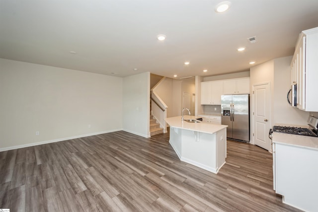 kitchen featuring appliances with stainless steel finishes, an island with sink, sink, white cabinetry, and hardwood / wood-style flooring