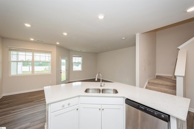 kitchen with a center island with sink, stainless steel dishwasher, light stone countertops, hardwood / wood-style flooring, and sink