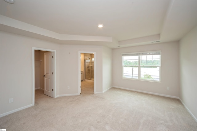 unfurnished bedroom featuring connected bathroom, light carpet, and a walk in closet