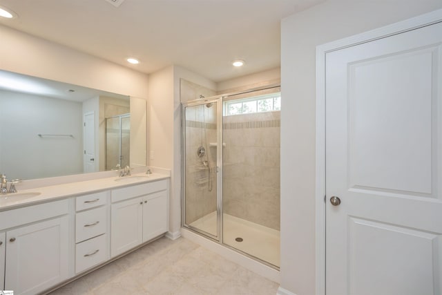 bathroom featuring a shower with shower door, double sink vanity, and tile patterned flooring