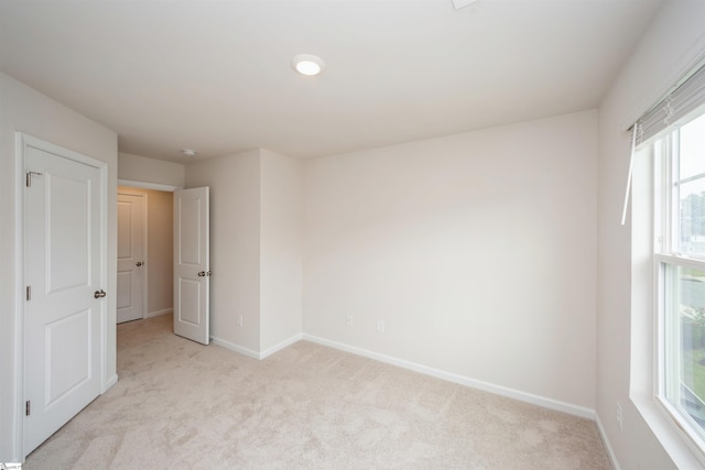 unfurnished bedroom featuring light carpet and multiple windows