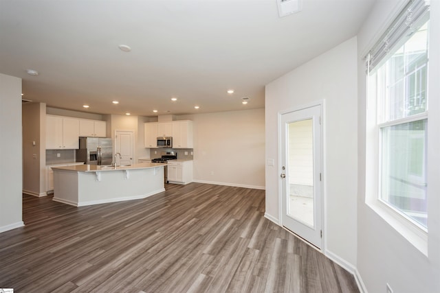 kitchen featuring stainless steel appliances, a kitchen island with sink, hardwood / wood-style floors, and white cabinetry