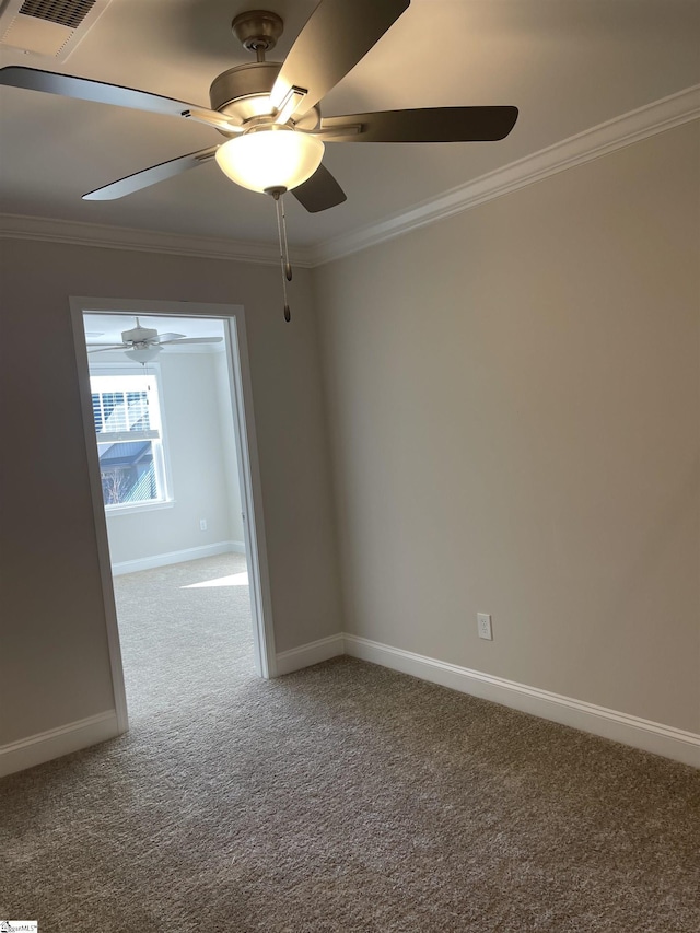 carpeted spare room featuring ceiling fan, baseboards, crown molding, and visible vents