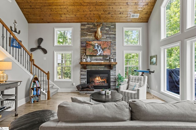 living room featuring light hardwood / wood-style floors, wooden ceiling, a fireplace, and high vaulted ceiling