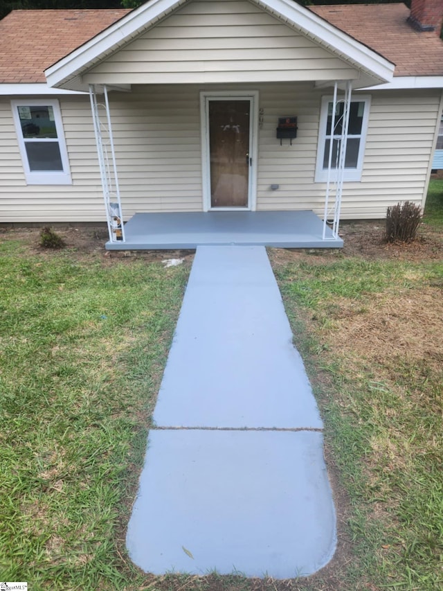 property entrance with a porch and a lawn