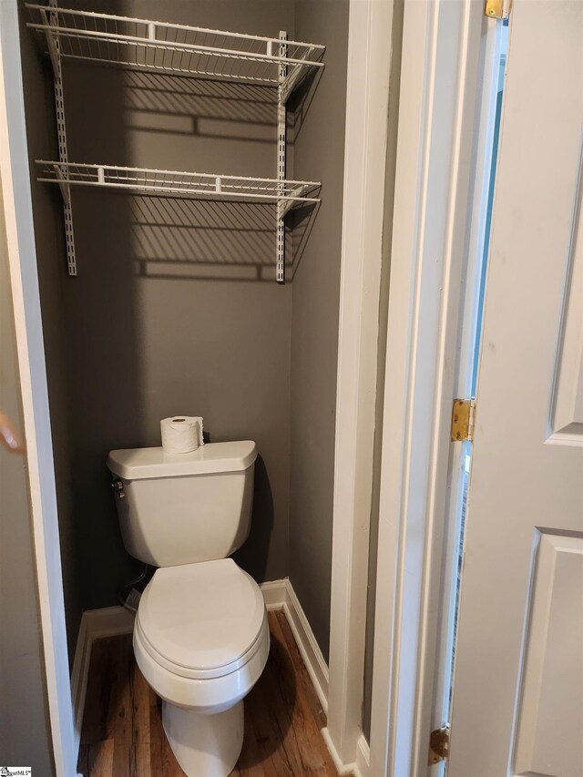 bathroom with wood finished floors, toilet, and baseboards