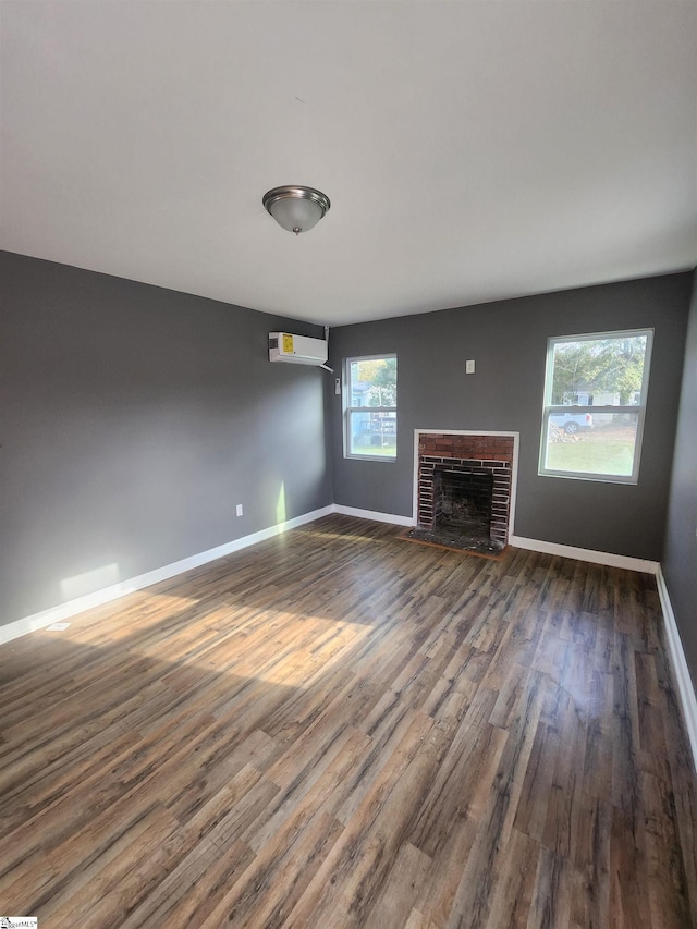 unfurnished living room featuring dark wood-style floors, an AC wall unit, a fireplace, and baseboards