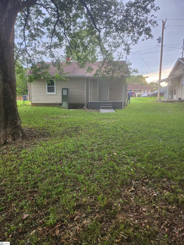 back of property with entry steps and a yard