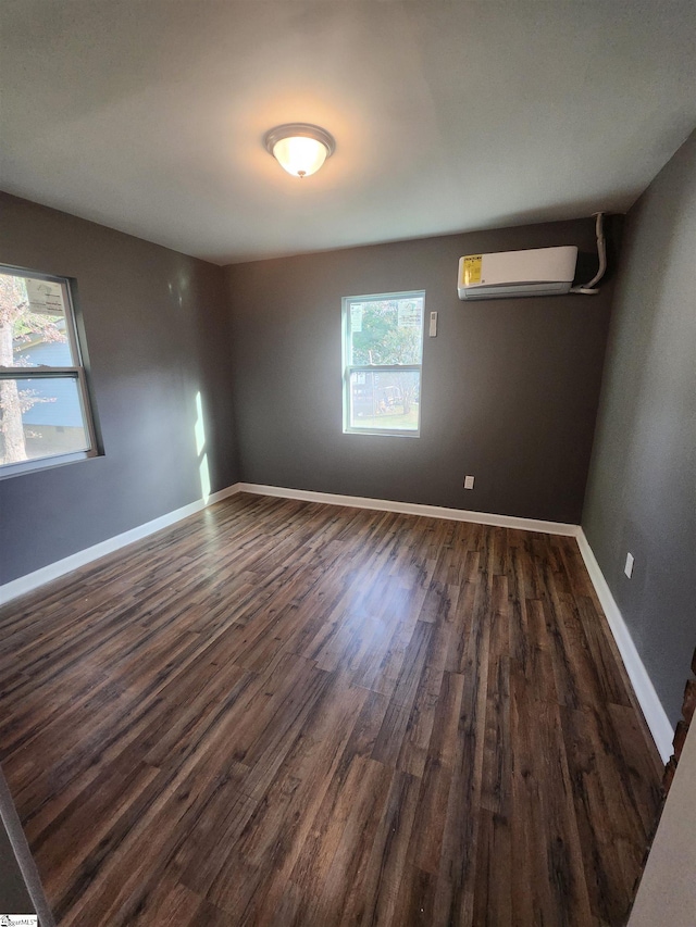 empty room with dark wood-type flooring, baseboards, and a wall mounted AC