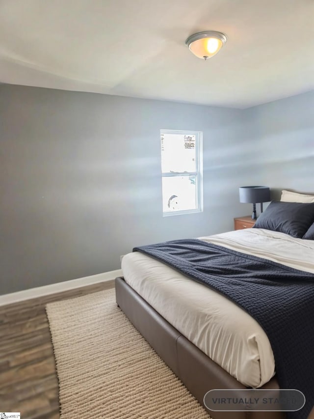 bedroom with baseboards and wood finished floors