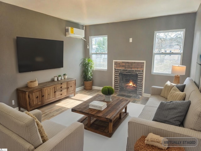 living area with light wood-style floors, a wall unit AC, a fireplace, and baseboards