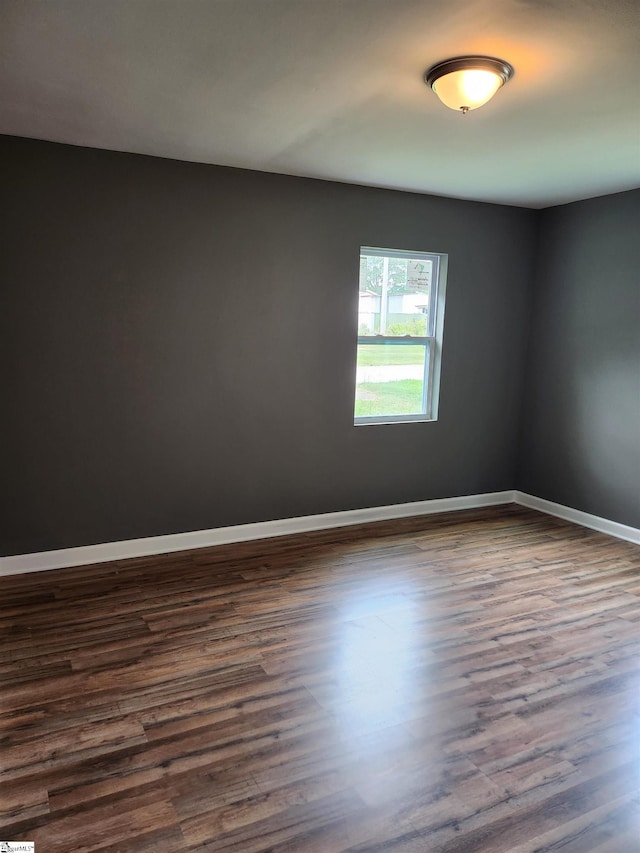 empty room featuring dark wood finished floors and baseboards