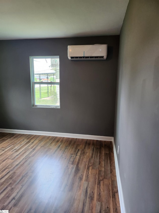 unfurnished room featuring a wall mounted AC, wood finished floors, and baseboards