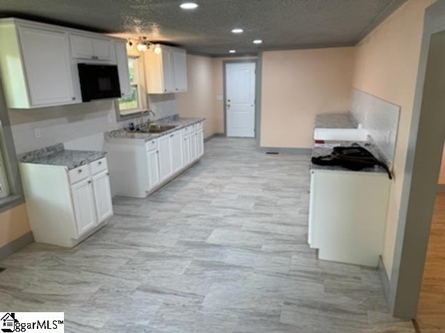 kitchen featuring sink, a textured ceiling, and white cabinets