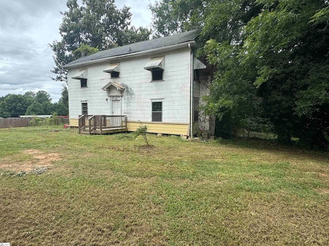 back of property featuring a deck and a yard