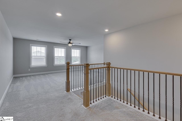 hallway with an upstairs landing, recessed lighting, baseboards, and light colored carpet