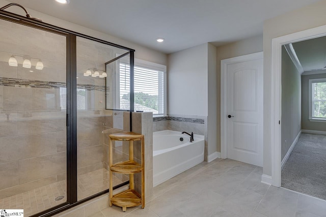 bathroom with a healthy amount of sunlight, a stall shower, baseboards, and a bath