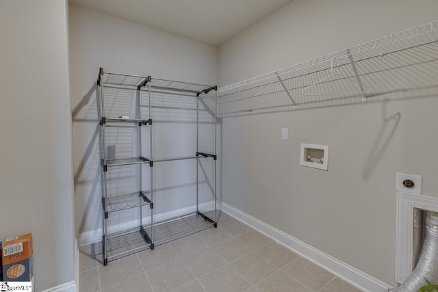 clothes washing area with light tile patterned floors, hookup for a washing machine, hookup for an electric dryer, laundry area, and baseboards