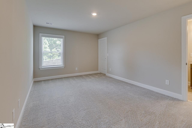 spare room featuring baseboards, recessed lighting, visible vents, and light colored carpet