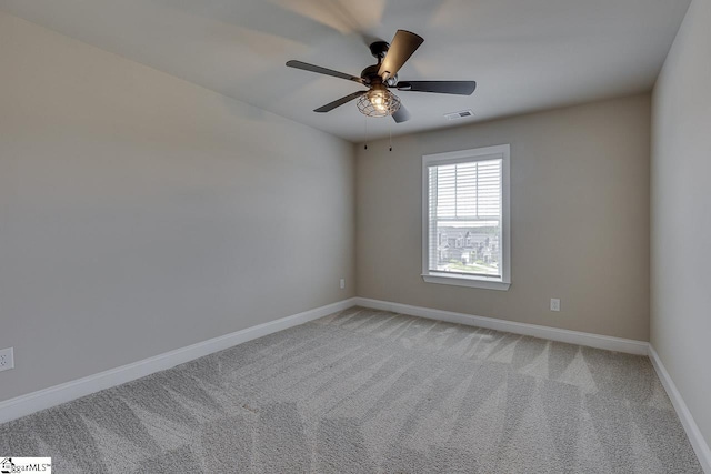 carpeted spare room with a ceiling fan, visible vents, and baseboards