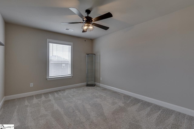 empty room featuring light carpet, a ceiling fan, visible vents, and baseboards