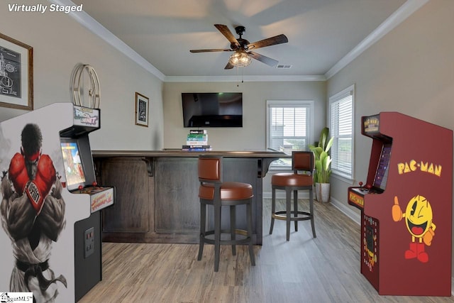 bar featuring ornamental molding, visible vents, light wood-style floors, and a ceiling fan