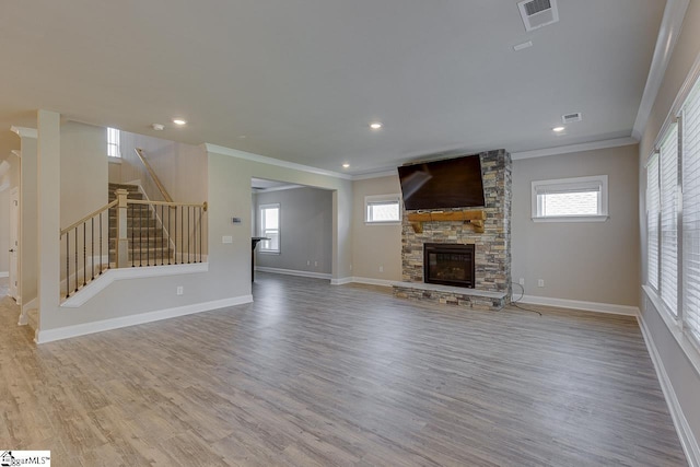 unfurnished living room with stairs, a stone fireplace, light wood-type flooring, and visible vents