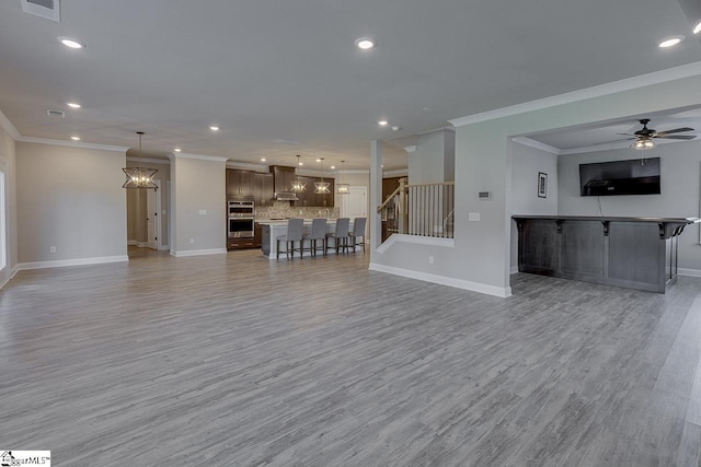 unfurnished living room featuring light wood-style floors, visible vents, stairway, and baseboards