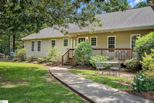 back of house with a lawn and roof with shingles