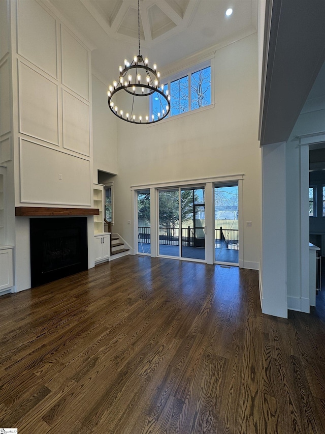 unfurnished living room with dark hardwood / wood-style floors, a high ceiling, coffered ceiling, a notable chandelier, and beamed ceiling