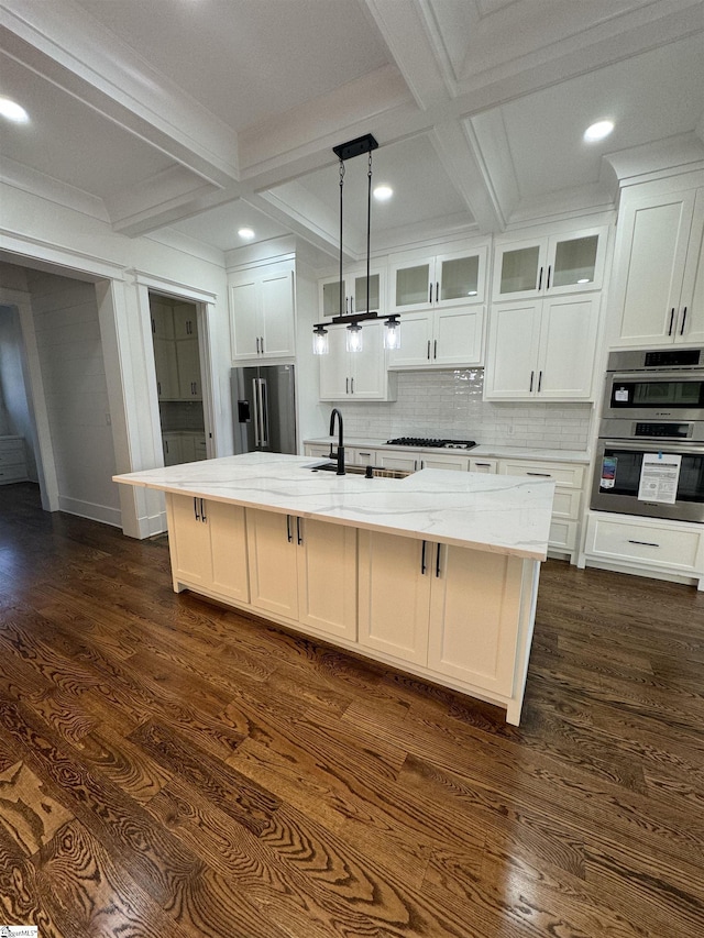 kitchen featuring stainless steel appliances, light stone countertops, and a kitchen island with sink